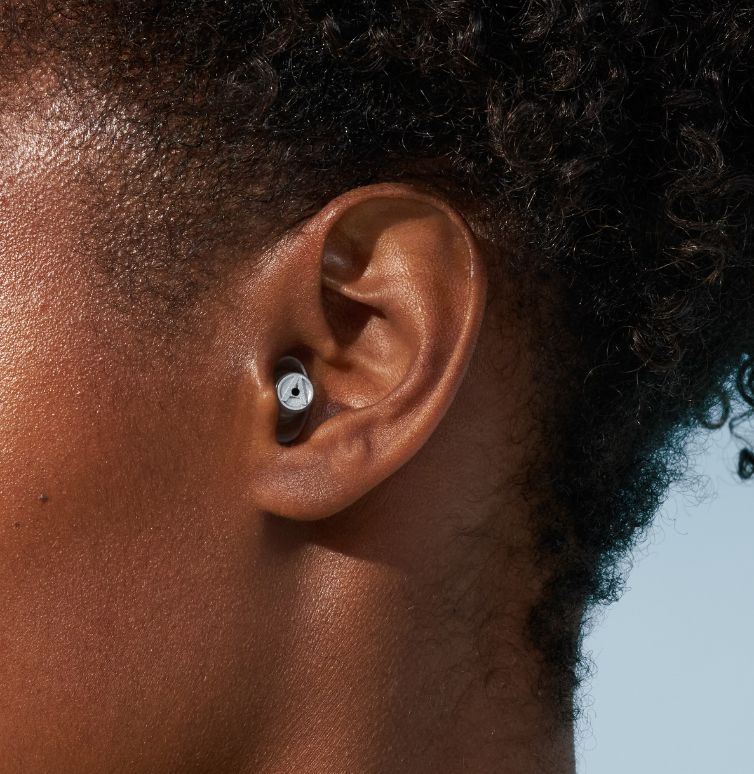 Gros plan sur l’oreille d’une femme avec des bouchons d’oreille Alpine.
