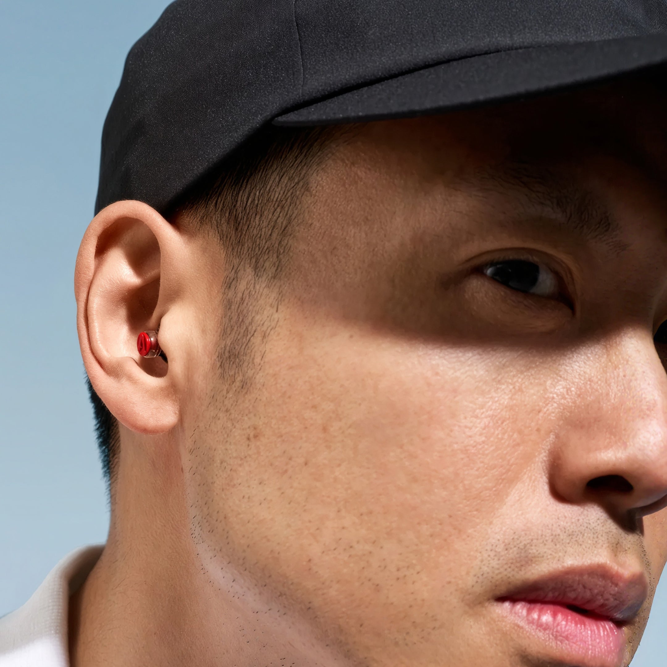 Close-up of a man in a black cap wearing an Alpine Formula 1 earplug