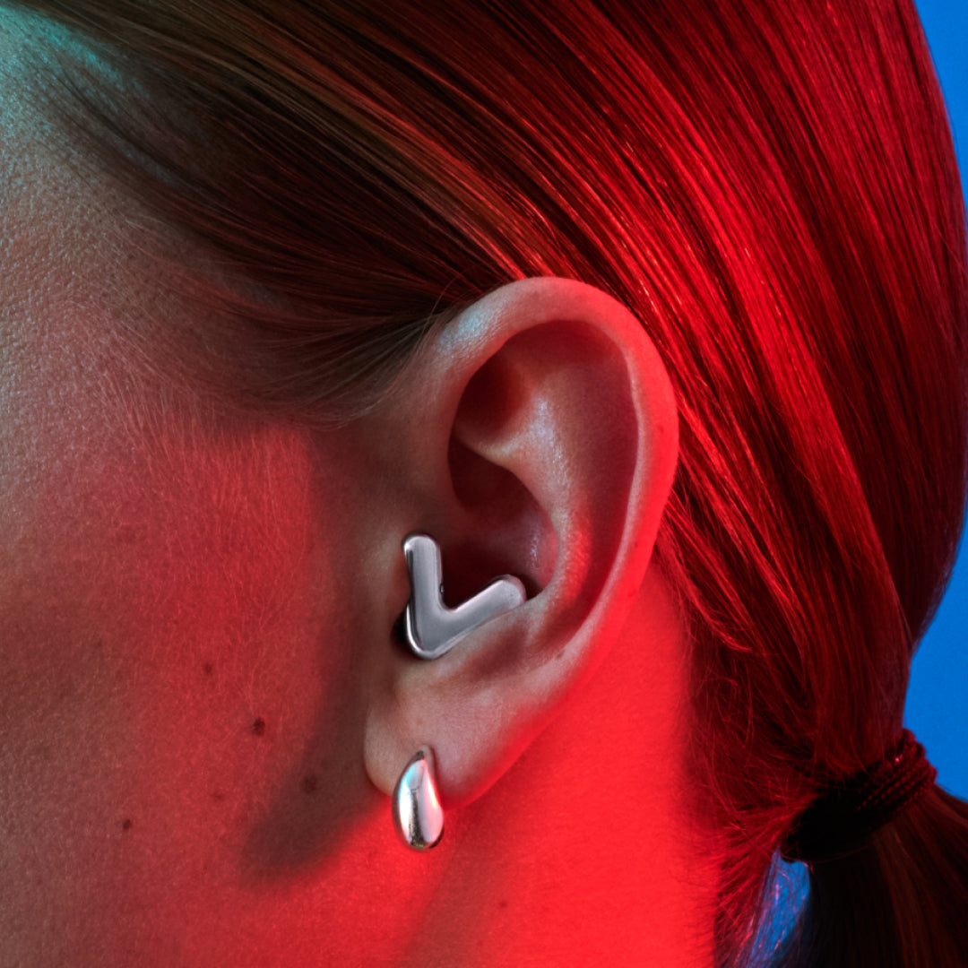 Detailed image of an ear with an Alpine Tune earplug in silver showing the snug fit in ear